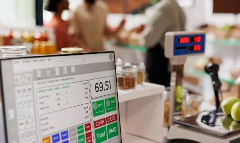 A shop owner serving a customer at a point-of-sale terminal